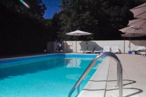 a swimming pool with chairs and umbrellas next to it at Chez Fins Bois in Néré