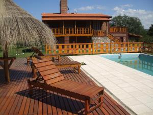 una terraza con bancos y una casa con piscina en Apart Cabañas Altos de Vaquerias en Valle Hermoso