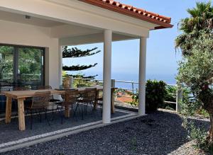 a patio with a table and chairs and a view of the ocean at Calheta Boutique Houses in Arco da Calheta