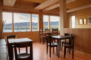 uma sala de jantar com mesas, cadeiras e janelas em Hostería La Soberana em El Calafate