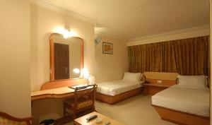 a hotel room with two beds and a mirror at Epsilon Hotel in Ahmedabad