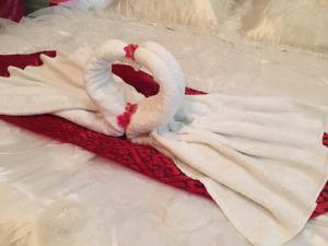 two white swans laying on a red blanket at Isra Hotel in Nablus