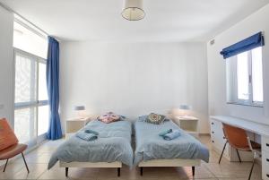 セント・ポールズ・ベイにあるHV12 - Sea Front Penthouseのベッド2台、デスク、窓が備わる客室です。