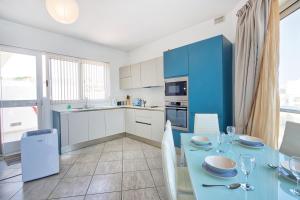 eine Küche mit einem Tisch und einer blauen Küche in der Unterkunft HV12 - Sea Front Penthouse in St Paul's Bay