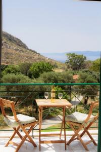 a table with wine glasses and two chairs on a balcony at Kykeon Studios in Katelios