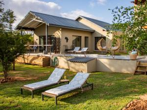a house with two lounge chairs in the yard at Rafiki Bush Lodge in Hoedspruit