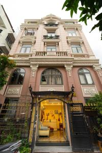 un grand bâtiment rose avec une porte ouverte dans l'établissement Maison Royale, à Hô-Chi-Minh-Ville