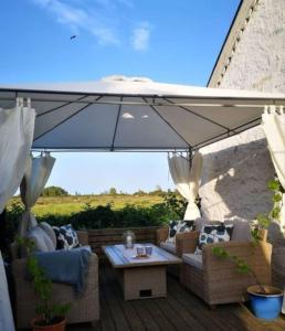 une terrasse avec un parasol, des canapés et une table dans l'établissement Unikt läge med stora Alvaret som närmsta granne, à Mörbylånga