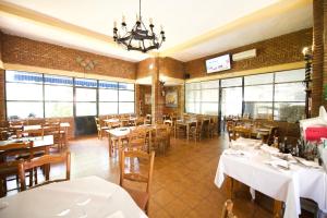 un restaurante con mesas y sillas blancas y ventanas en Aranjuez Camping & Bungalows, en Aranjuez