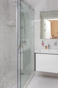 a bathroom with a glass shower and a sink at Casa Leto in Saint Petersburg