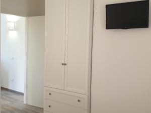 ポルト・ロトンドにあるResidence Porto Rotondoの白いキャビネットと壁掛けテレビが備わる客室です。