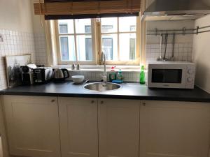 a kitchen with a microwave, sink, and dishwasher at City Studios in Amsterdam