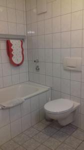 La salle de bains blanche est pourvue de toilettes et d'une baignoire. dans l'établissement Domizil, à Bad Bertrich
