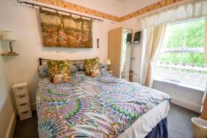 a bedroom with a bed with a colorful comforter and a window at Gorphwysfa House B & B in Betws-y-coed
