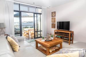 a living room with a couch and a flat screen tv at Luxury Ocean View 2 Bed Apartment 259 Eden on the Bay, Blouberg, Cape Town in Big Bay
