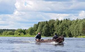 twee mensen in een boot op een rivier bij Kukkolankoski Resort - Vierastalot in Kukkola