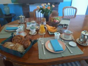 - une table avec un petit-déjeuner composé de pain et de jus de fruits et un ordinateur portable dans l'établissement Les Convertigues, à Montjoire