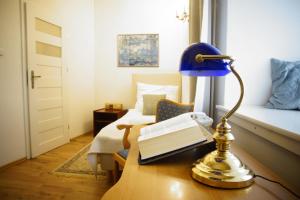 een lamp op een bureau met een boek en een bed bij Pokoje Gościnne Dom Literatury in Warschau