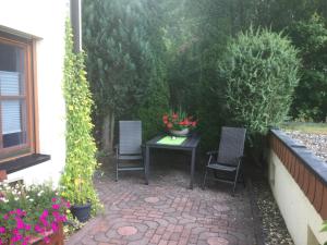 a patio with two chairs and a table with flowers at FW Sonnenschein in Wechterswinkel