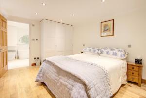 a white bedroom with a bed and a wooden floor at Luxury Apartments - 39 Rodney Road Apartment in Cheltenham