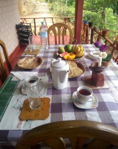 een tafel met een geruite tafeldoek met fruit erop bij Hidden Slope Cottage in Ella