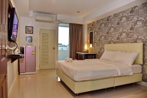 a bedroom with a large bed and a brick wall at BaanHim in Rayong