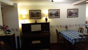 einen Tisch und ein Klavier in einem Zimmer mit einem Tisch und einem Tisch in der Unterkunft Sunnyside B&B in Balloch