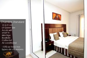 Cartel de un dormitorio con cama y espejo en Les Residences MAMOUNE en Dakar