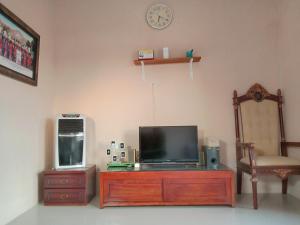 a tv on a dresser with a chair and a clock at Guesthouse - Lubna Homestay in Kuningan