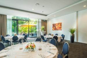 una sala de conferencias con mesas y sillas y una gran ventana en Fletcher Hotel-Restaurant de Wageningsche Berg en Wageningen