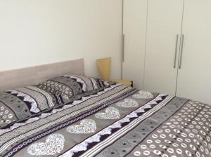 a bed with gray and white sheets and pillows at LEMAN in Thonon-les-Bains