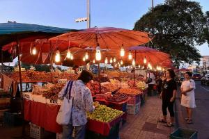 a group of people standing at an outdoor fruit market at The Port Hostel in Suratthani