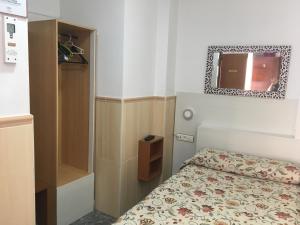 a small bedroom with a bed and a mirror at Pensión El Hidalgo in Granada