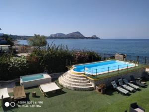 a swimming pool next to a body of water at Villa Silvia in Casteldaccia