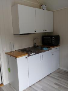 cocina con armarios blancos, fregadero y microondas en Nedre Amla Fjord Apartment, en Kaupanger