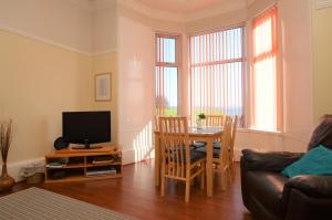 a living room with a table and a tv at Sebright Holiday Apartment in Dunoon