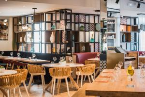 un restaurante con mesas, sillas y estanterías en Golden Tulip Aix en Provence, en Aix-en-Provence