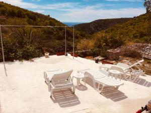 a group of white chairs and tables on a patio at Villa Duboka, Otok Vis in Komiža