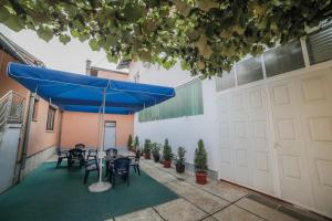 a patio with tables and chairs under a blue umbrella at Guesthouse Tanja in Banja Luka