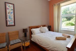 1 dormitorio con cama, ventana y silla en Sebright Holiday Apartment, en Dunoon