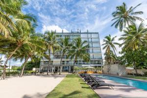 ein Hotel mit Palmen und einem Pool in der Unterkunft Beachfront King Bed Privacyjacuzzifullkitchen in La Puntica de Juan Dolio