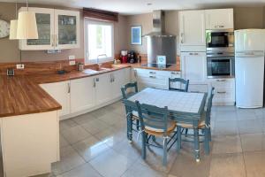 une cuisine avec des armoires blanches et une table et des chaises dans l'établissement Appartement au Coeur de la Provence, à Beaumes-de-Venise
