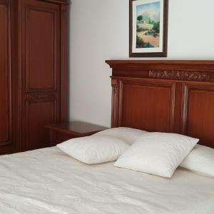 Bett mit einem Kopfteil aus Holz und zwei weißen Kissen in der Unterkunft Alojamiento Rural Jacinta in Torres de Albanchez