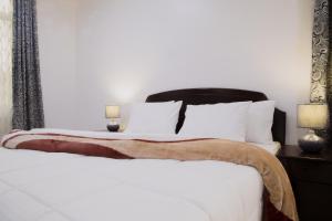 sypialnia z białym łóżkiem z czarnym zagłówkiem w obiekcie Two Mountains Lodge w mieście Arusza
