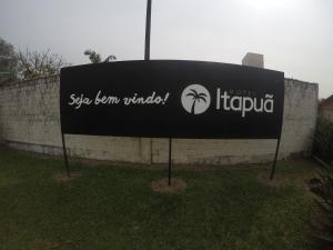 a sign in the grass in front of a wall at Motel Itapuã III Fx Rosário do Sul in Santa Maria