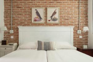 ein Schlafzimmer mit einem weißen Bett und einer Ziegelwand in der Unterkunft Luxury Apartment museum mile. Air condicioning in Madrid