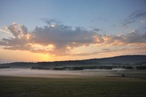 un campo con niebla en un campo con puesta de sol en La Cachotière en La Chaux-du-Milieu