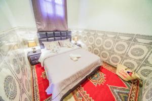 a small bedroom with a bed with a red rug at Dar Widad in Ouarzazate