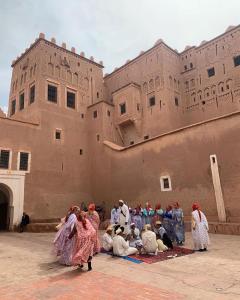 eine Gruppe von Menschen, die vor einem Gebäude sitzen in der Unterkunft Dar Widad in Ouarzazate