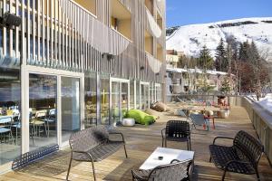 a patio with chairs and tables on a building at The People - Les 2 Alpes in Les Deux Alpes